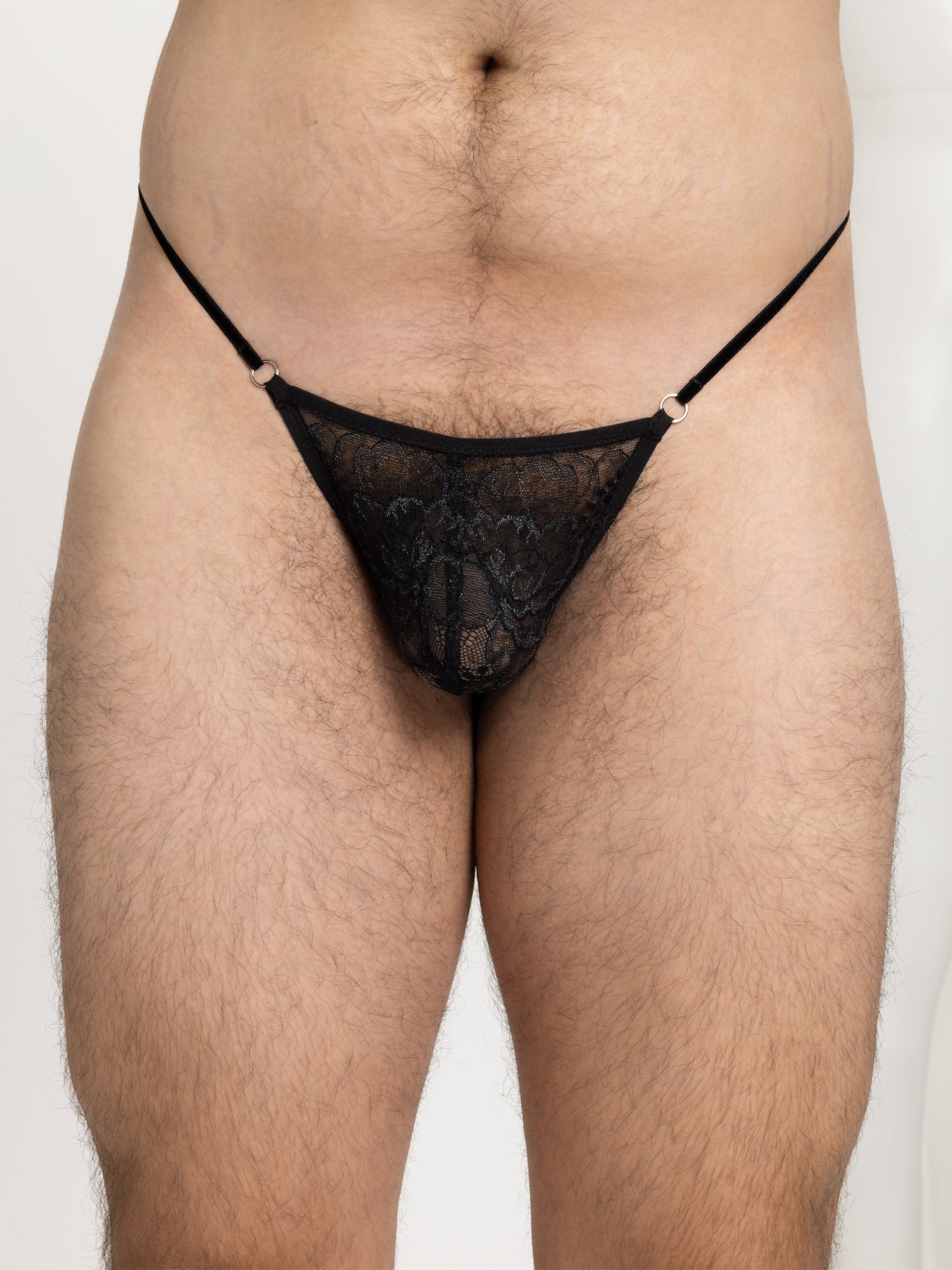 Close up view of a pouch fit mirco thong made with floral black lace, thin adjustable velvet straps and silver hardware.