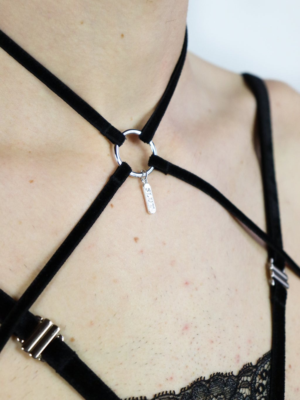 Close up view of a gender-free harness showing velvet straps details on the chest and a silver pendant around the neck.