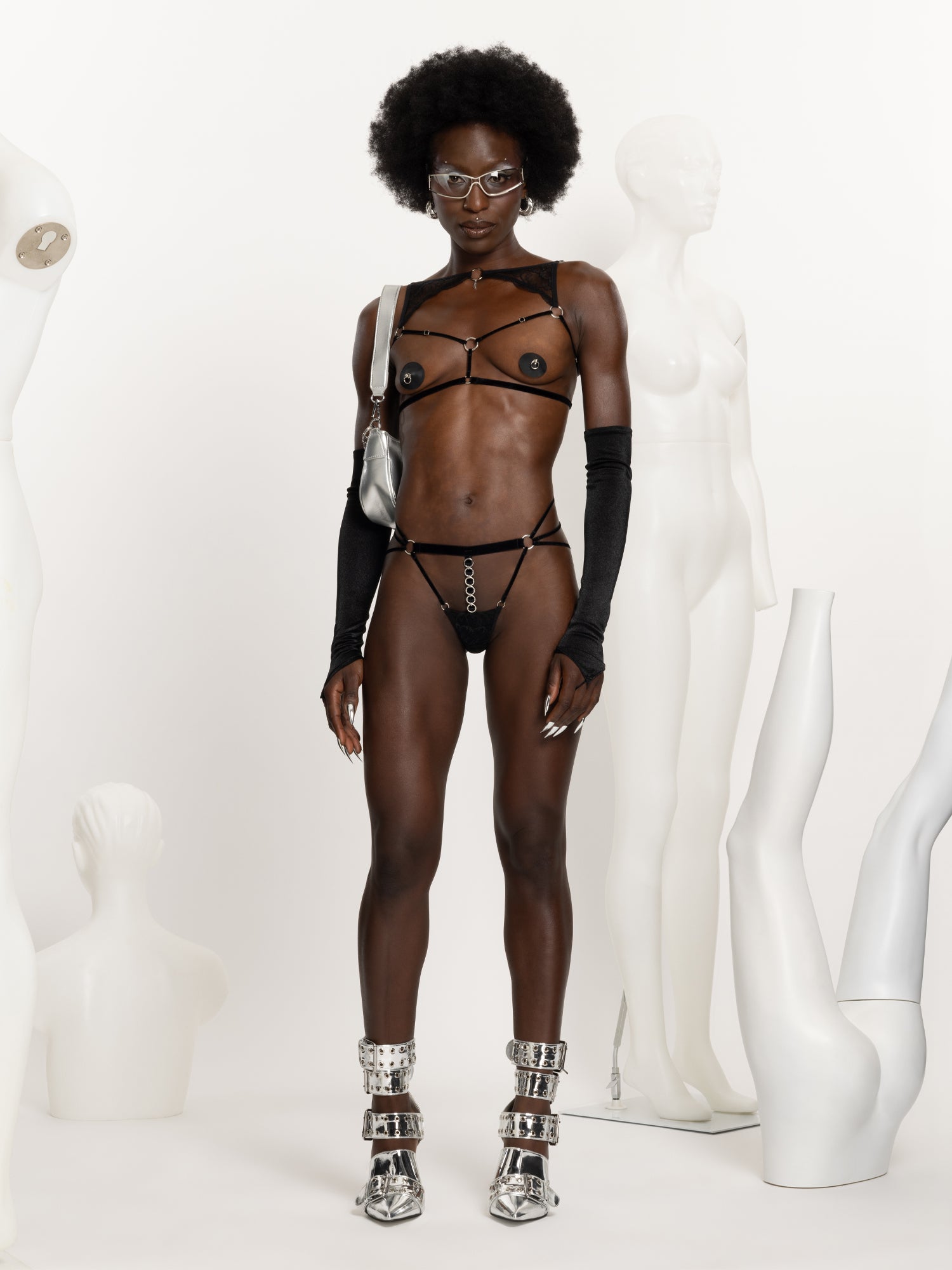 Full body view of model wearing a black velvet open cup harness with lace details above the chest, 'slut' engraved silver pendant and black velvet ouvert panties with silver o-rings details.