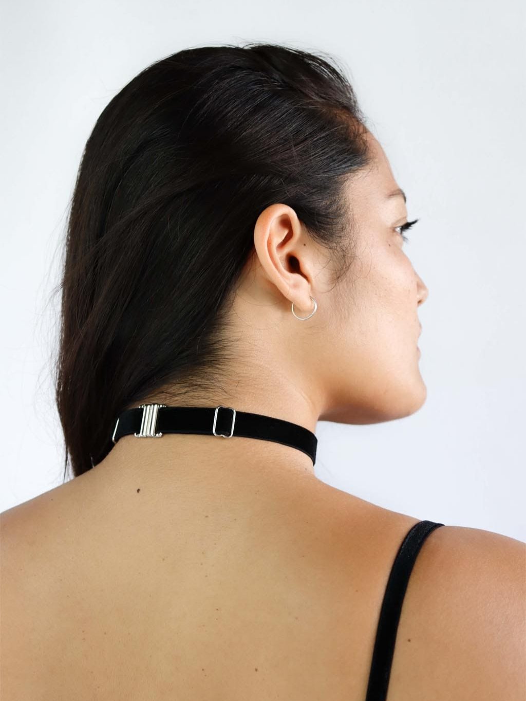 Back view of a woman wearing an adjustable black velvet choker with silver clasp.