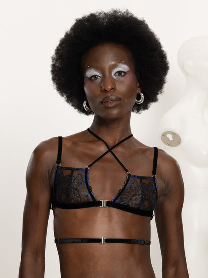 Model wearing an adjustable black and blue floral lace bra with soft velvet straps across the chest and waist and silver front closure.