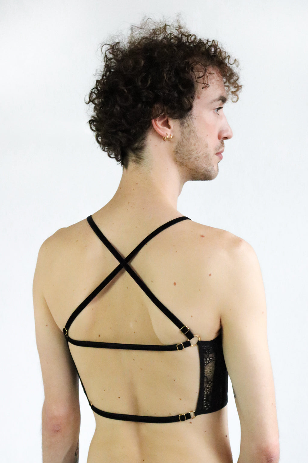 Back view of a unisex black lace crop top with 4 adjustable and interchangeable soft velvet straps and gold hardware. Size medium large.