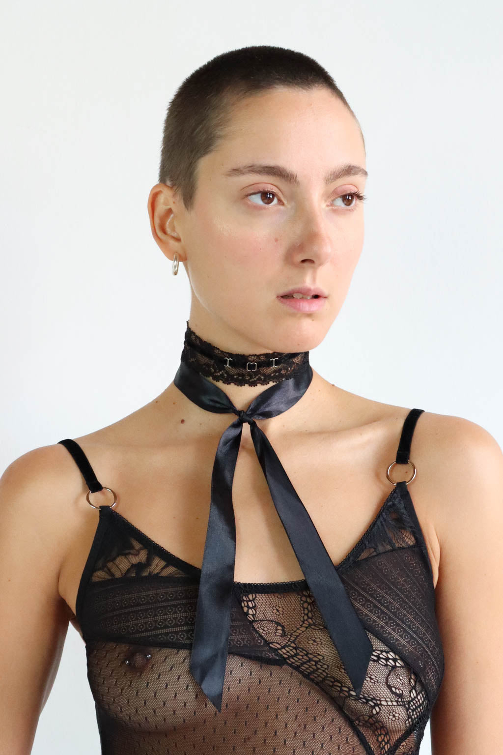 Black lace velvet choker with a satin ribbon tied in the front and silver hardware. Model also wears an eco-friendly lace crop top.