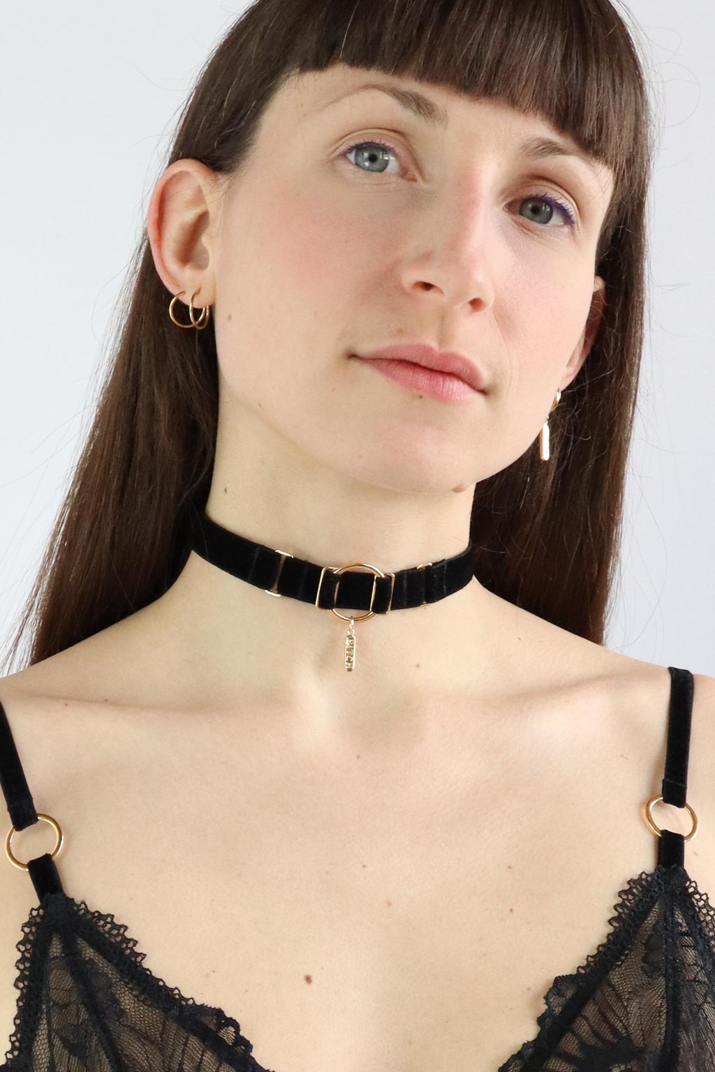 Woman wearing an O-ring black velvet choker with "Bitch" engraved gold pendant