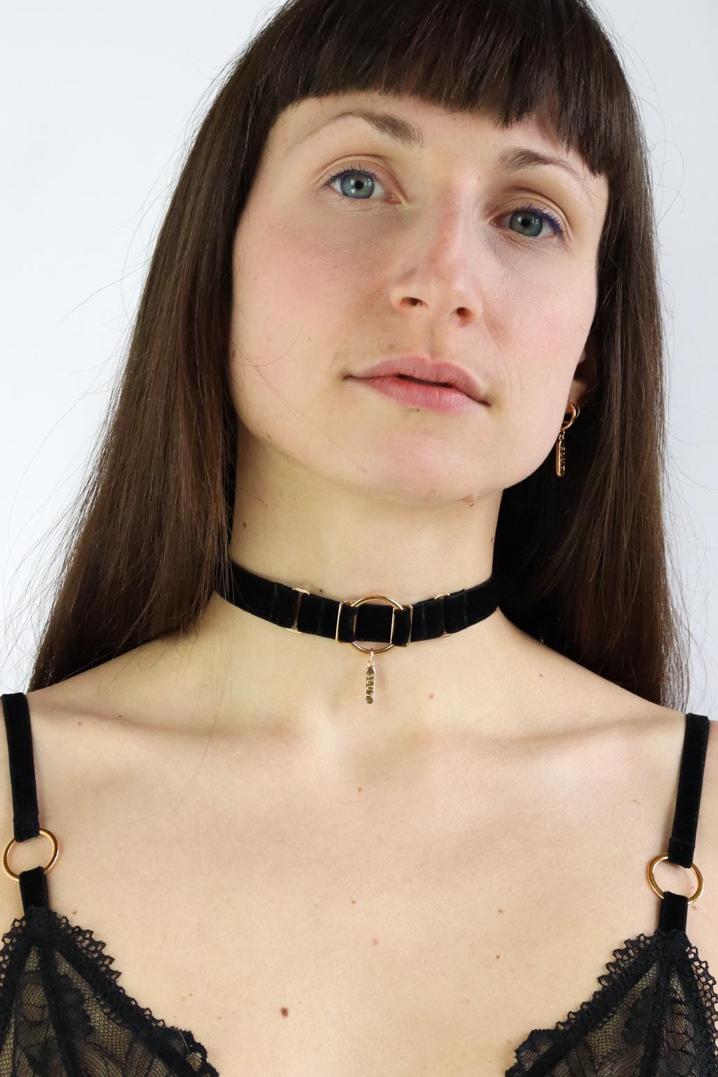 Woman wearing an O-ring black velvet choker with a gold "Slut" engraved charm