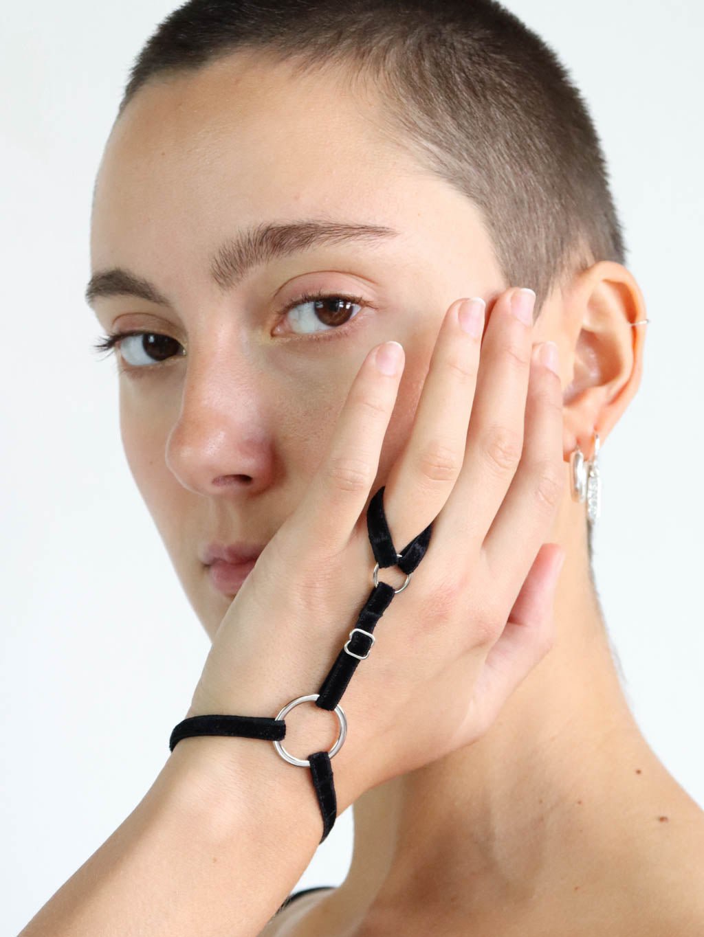 Adjustable black velvet hand harness with straps around the wrist and finger, and silver o-ring hardware.