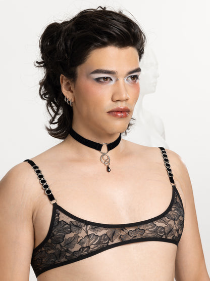 Model wearing a black velvet choker with a 4 o-rings charm attached to a black Swarovski crystal pendant. Also wears a gender free black lace micro bralette.