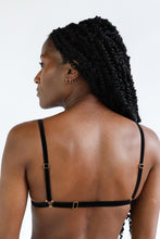 Load image into Gallery viewer, Back view of a woman wearing an adjustable bralette, with black velvet straps and gold hardware.
