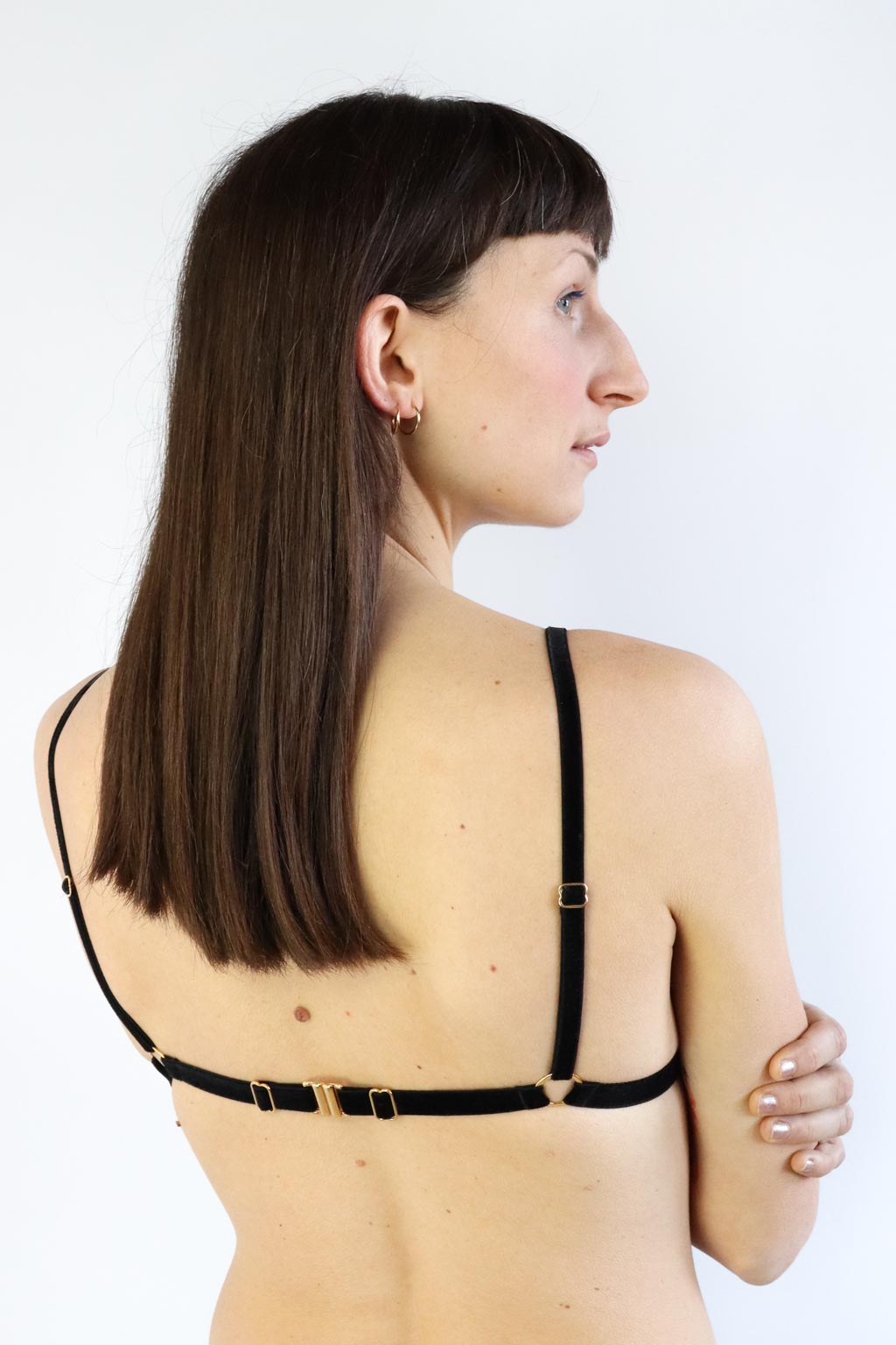 Back view of a fine lace adjustable bralette, with black velvet straps and gold clasp.