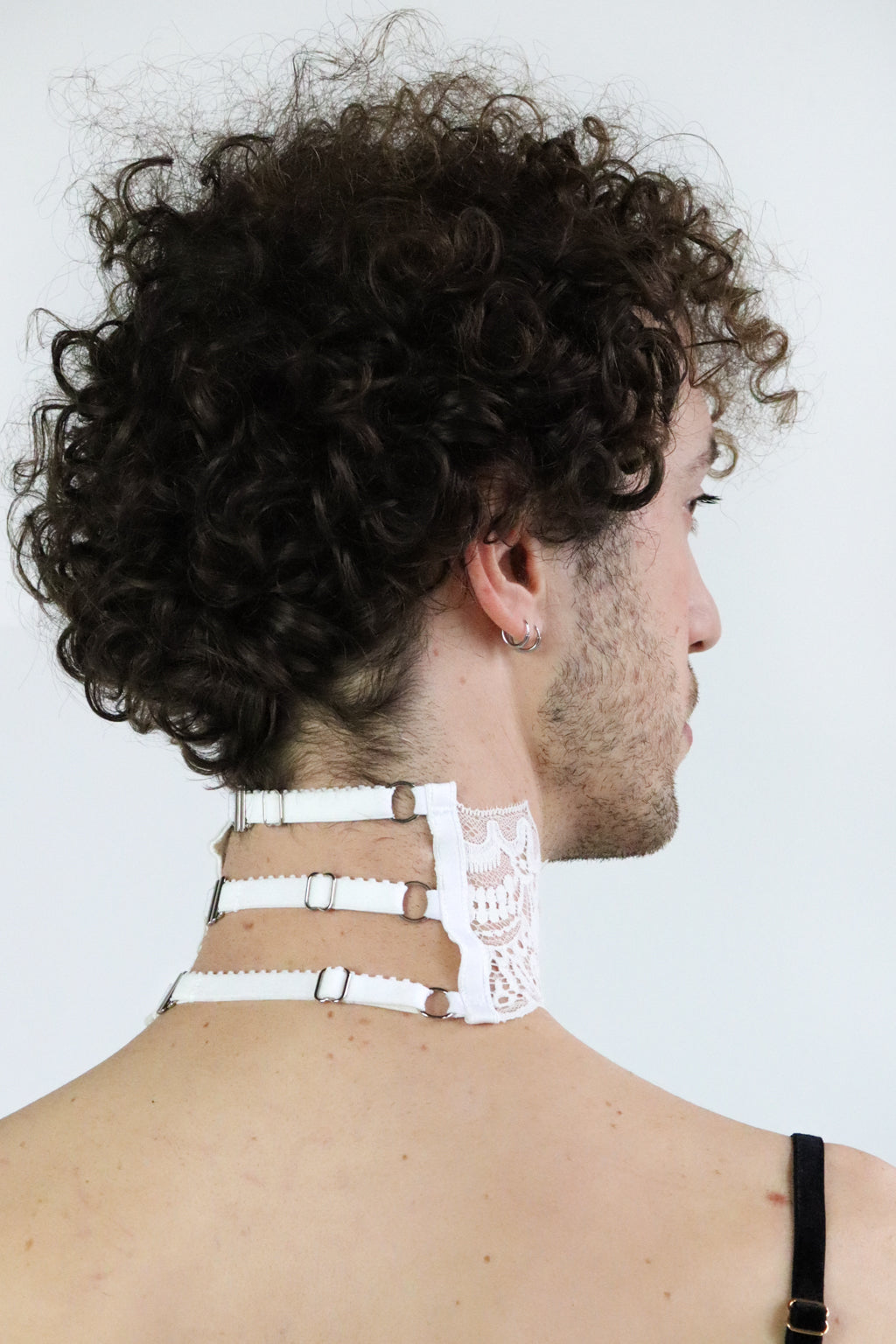 Back view of a unisex white lace collar with 3 adjustable straps and silver hardware.