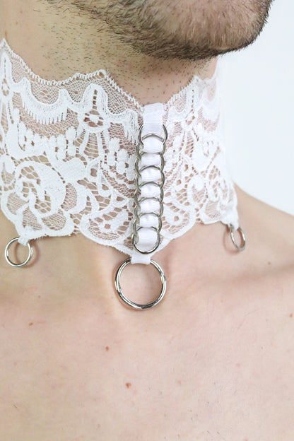 Close up view of unisex collar made of fine white patterned lace and silver o-rings attached.