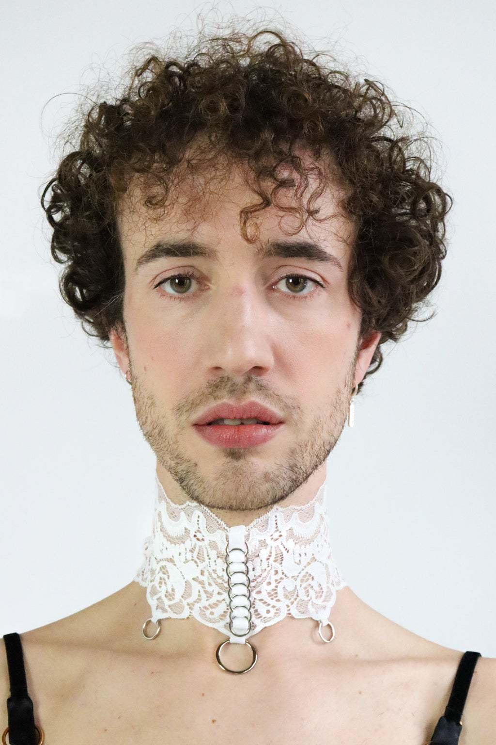 Front view of an adjustable white lace collar with silver o-rings details and pendants.