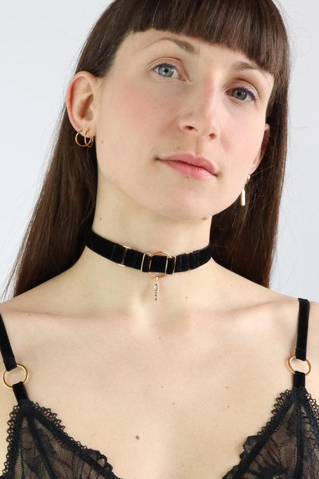 Woman wearing an O-ring black velvet choker with a gold charm with 