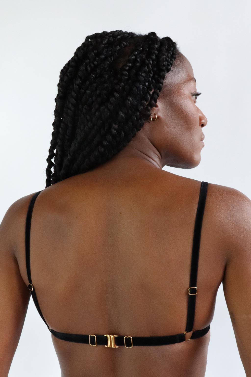 Back view of an ajustable bralette made of black velvet straps and eco-friendly golden clasp. 