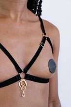 Load image into Gallery viewer, Close-up of a woman wearing an open cup bra harness with black velvet straps, gold hardware and a clear crystal pendant.
