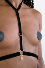 Load image into Gallery viewer, Close-up of a woman wearing a chest harness with black velvet straps, gold hardware and a transparent crystal pendant.
