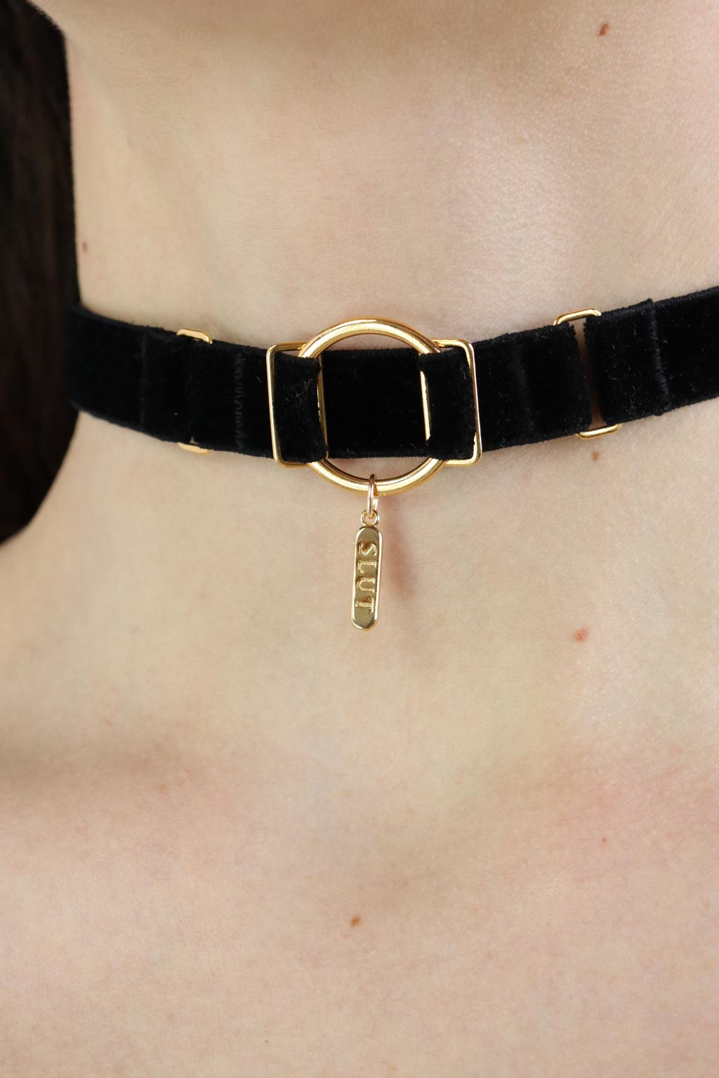 Close-up of a woman wearing an O-ring black velvet choker with a gold charm with 