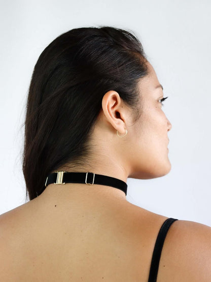 Back view of a woman wearing an adjustable black velvet choker with gold clasp and hardware.