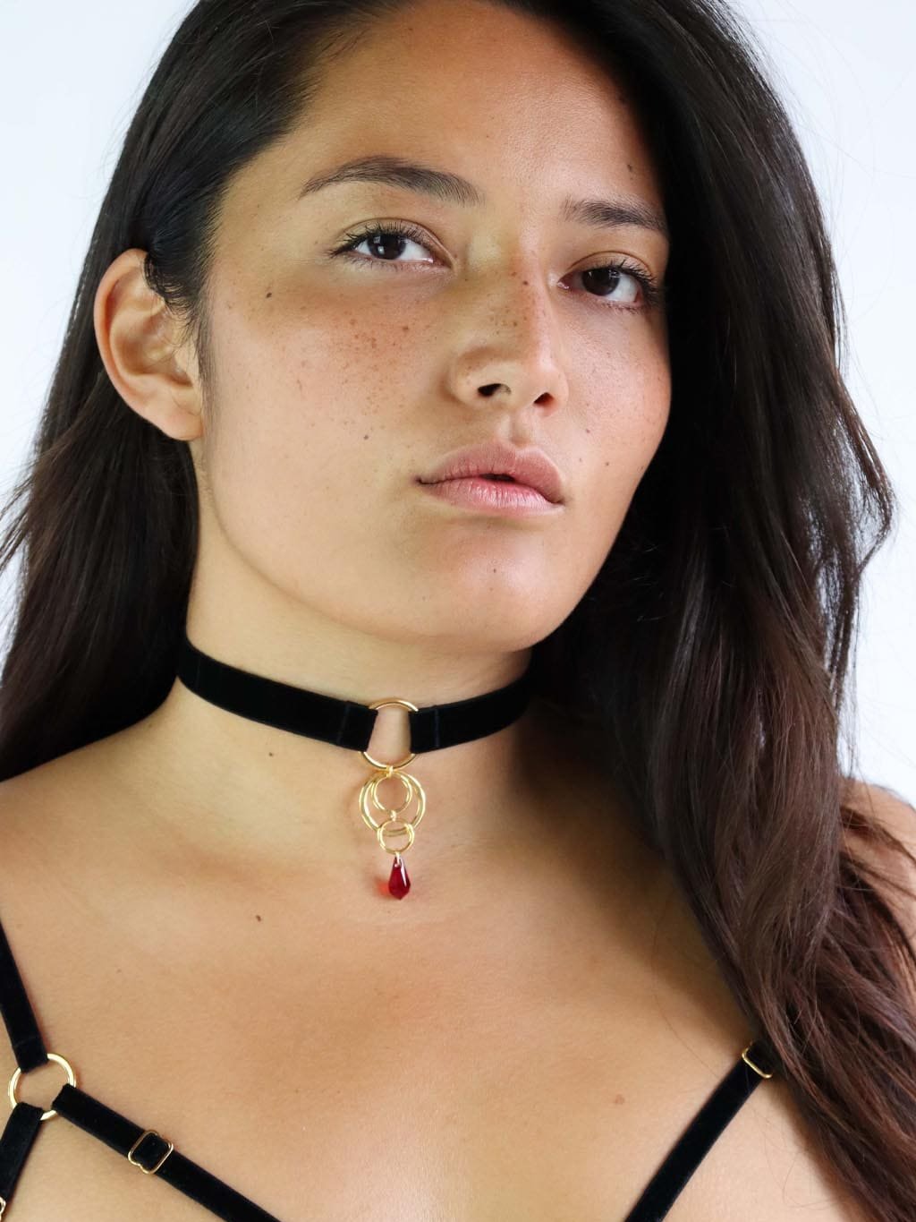 Black choker made of soft velvet strap and a charm with 4 gold o-rings and red Swarovski crystal pendant