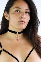 Load image into Gallery viewer, Woman wearing a black velvet choker with a gold 4 O-rings pendant and red crystal.
