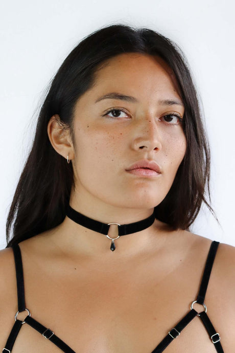 Woman wearing a black velvet choker with a silver O-ring pendant and black crystal.